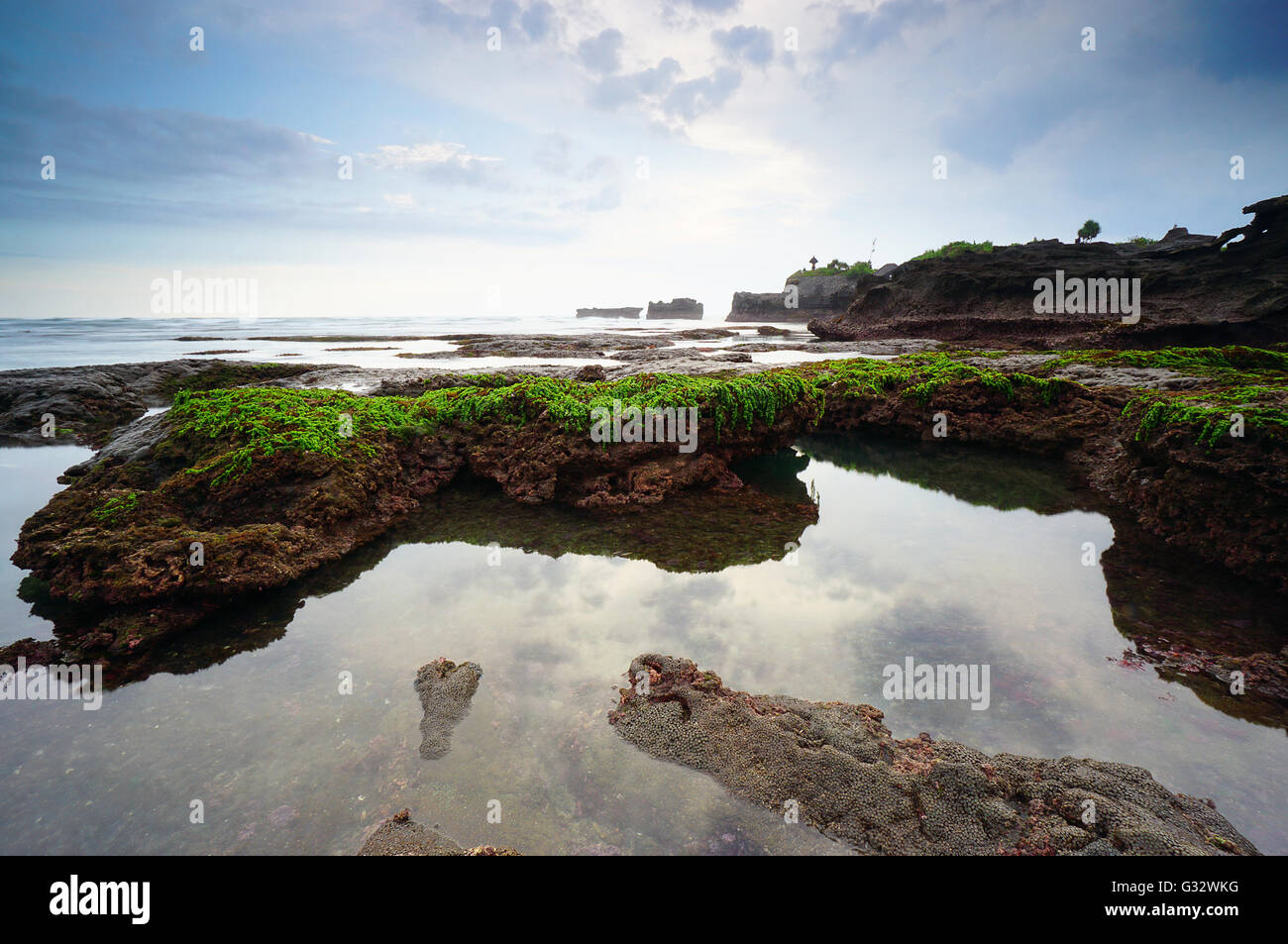 Moss covered rocks on Mengening beach at low tide, Bali, Indonesia Stock Photo