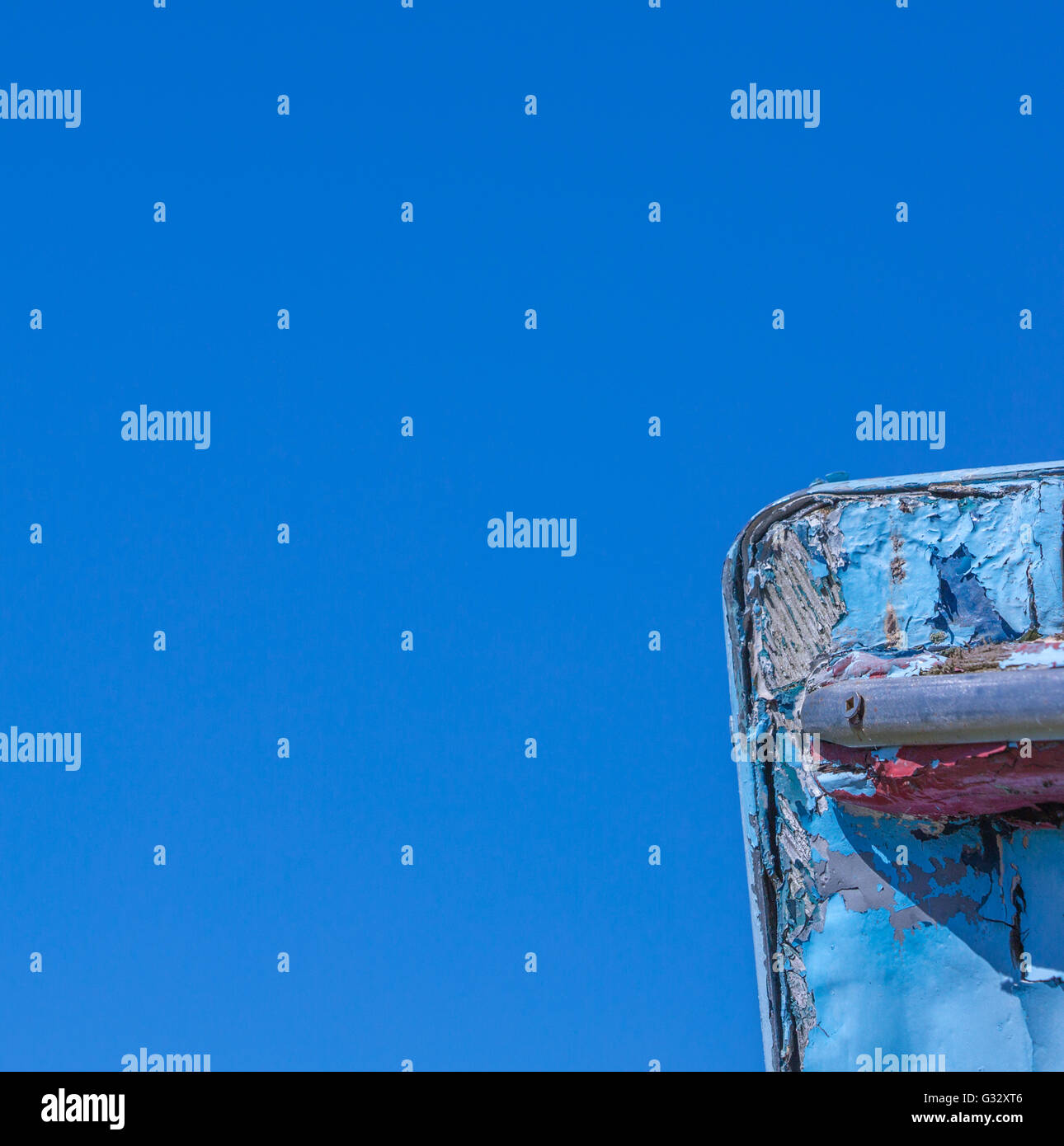 a detail image of an old wooden boat with peeling paint and signs of being exposed to the elements for years, brilliant blue sky Stock Photo