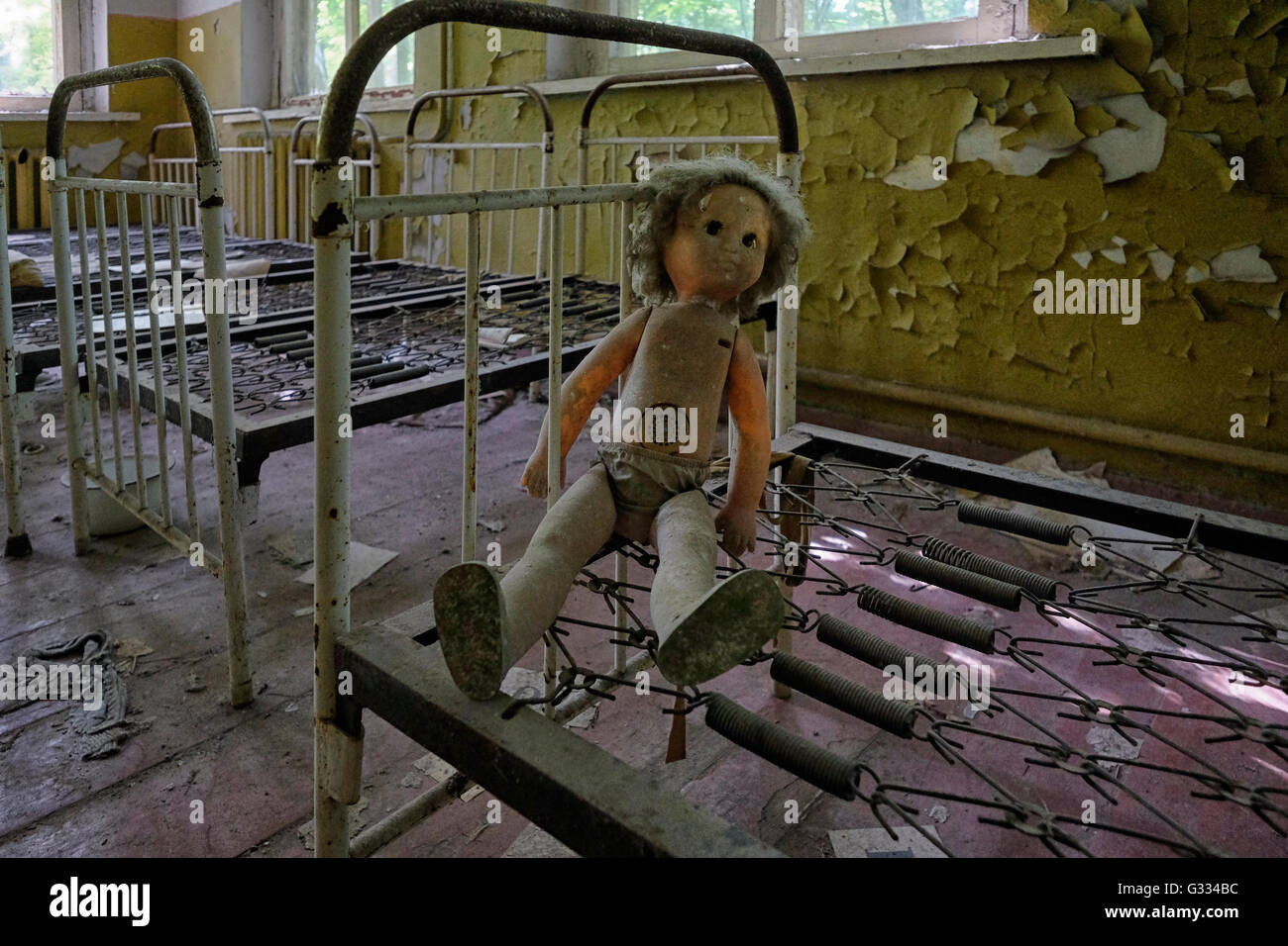 A doll lies among children's beds standing in the abandoned kindergarten of the deserted village of Kopachi which is still radioactive and contains high levels of plutonium, strontium-90 and caesium-137 located inside the Chernobyl Exclusion Zone in Ukraine on 04 June 2016. The Chernobyl accident occurred on 26 April 1986 at the Chernobyl Nuclear Power Plant in the city of Pripyat and was the worst nuclear power plant accident in history in terms of cost and casualties. Stock Photo