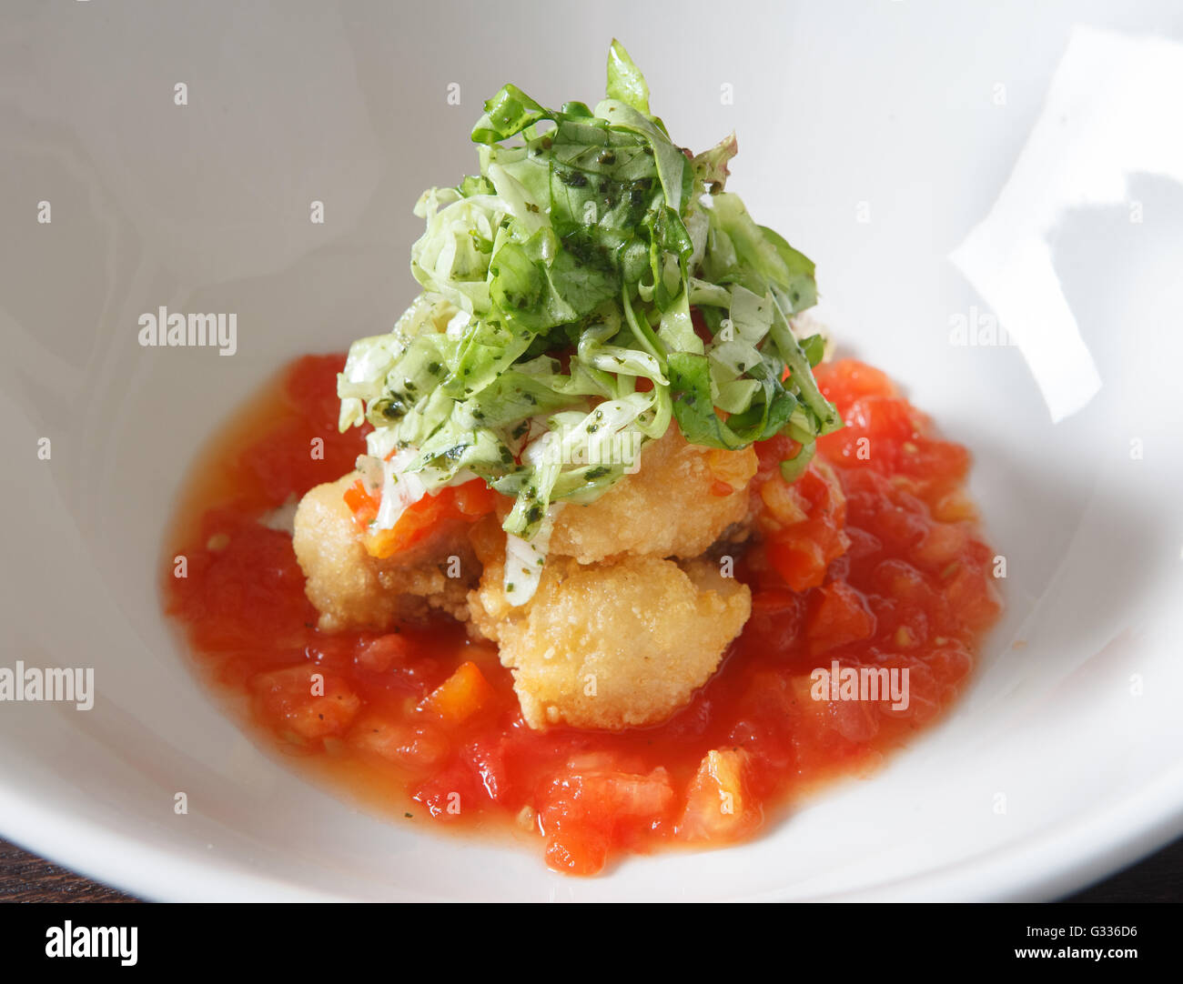 Fried chicken in breadcrumbs with tomato sauce  Decorating a dish of Japanese and Asian cuisine. White dish on wooden background Stock Photo