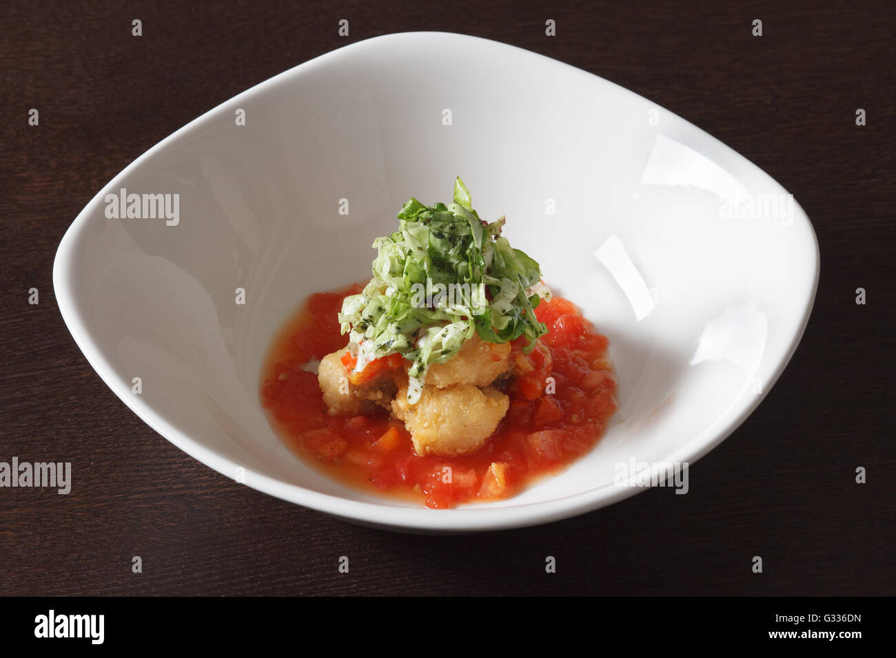 Fried chicken in breadcrumbs with tomato sauce  Decorating a dish of Japanese and Asian cuisine. White dish on wooden background Stock Photo