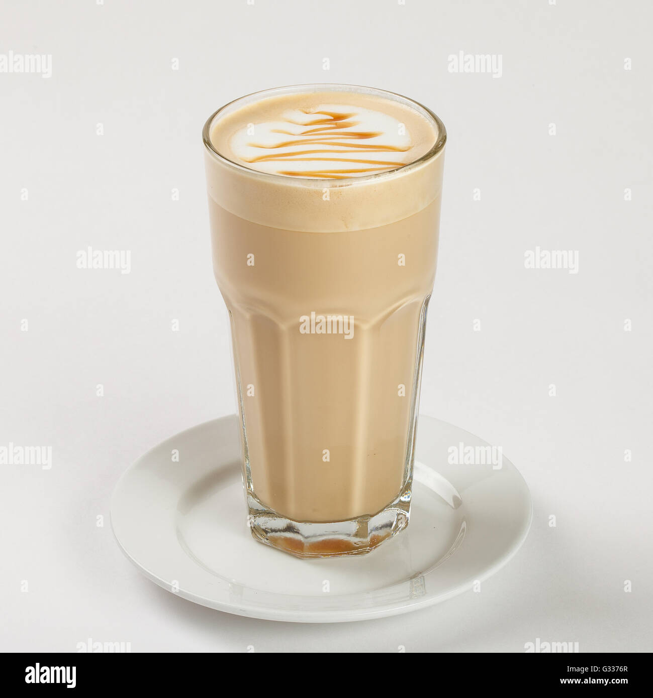 Delicious latte in a tall glass on the plate on white background. Close up side view. Stock Photo