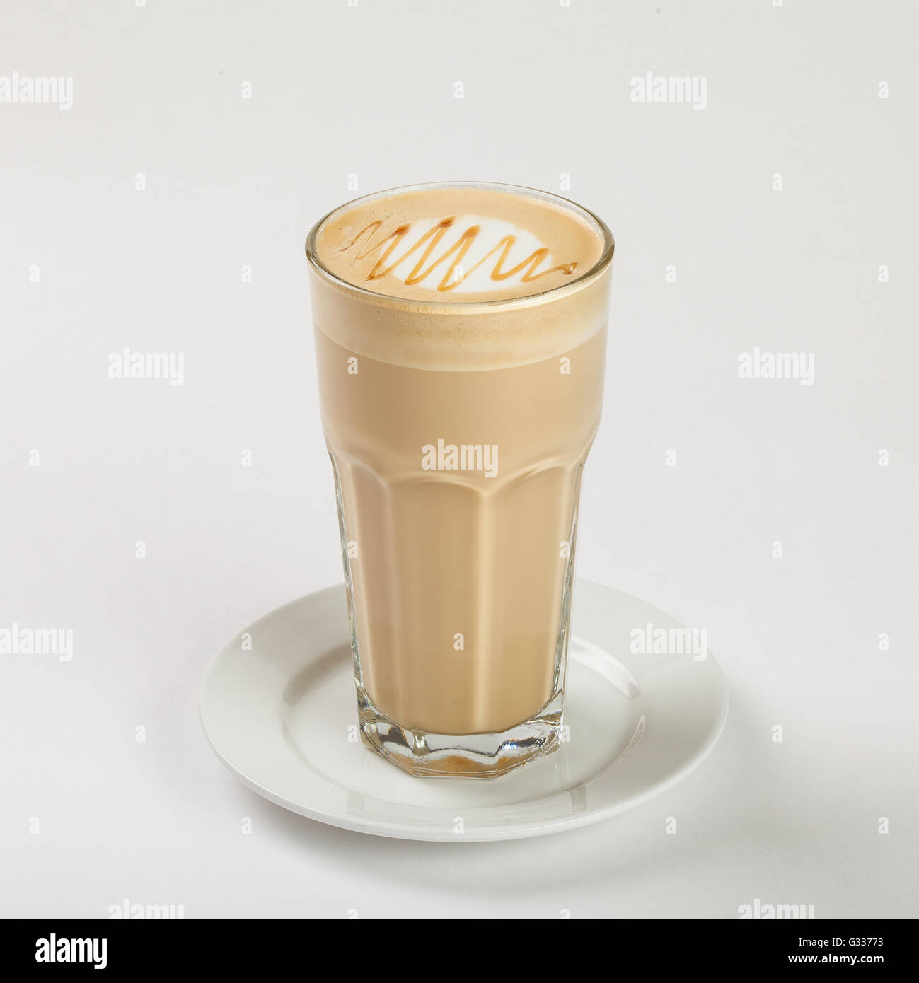 Delicious latte in a tall glass on the plate on white background. Stock Photo