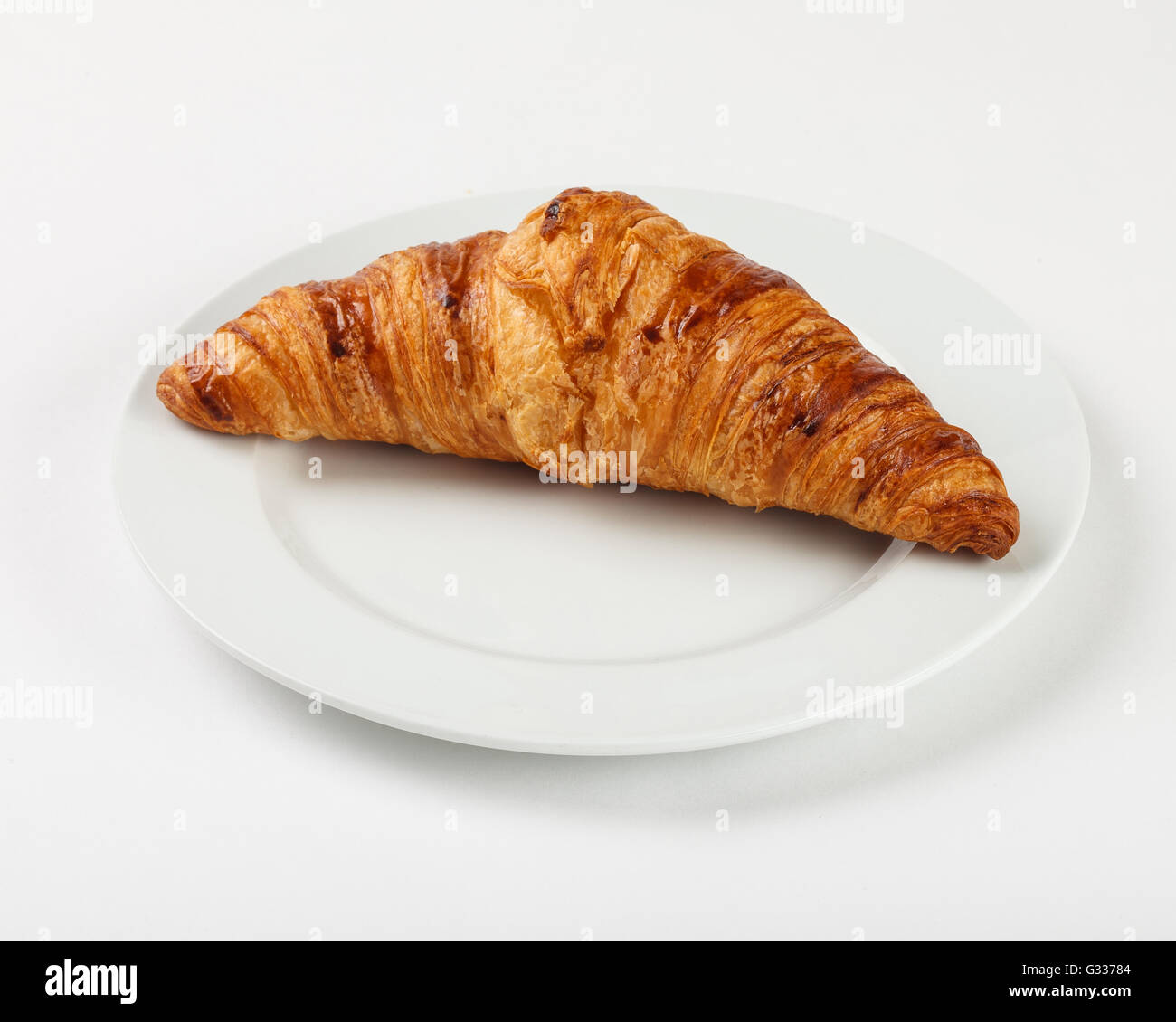 Delicious croissant on the plate on white background. Close up side view. Stock Photo