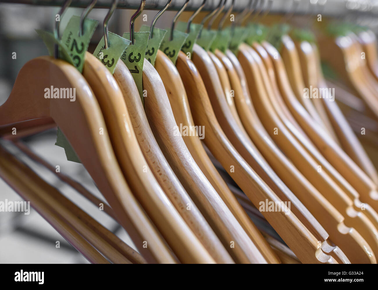 Wooden clothes hangers on a rail with numbered tickets. Stock Photo