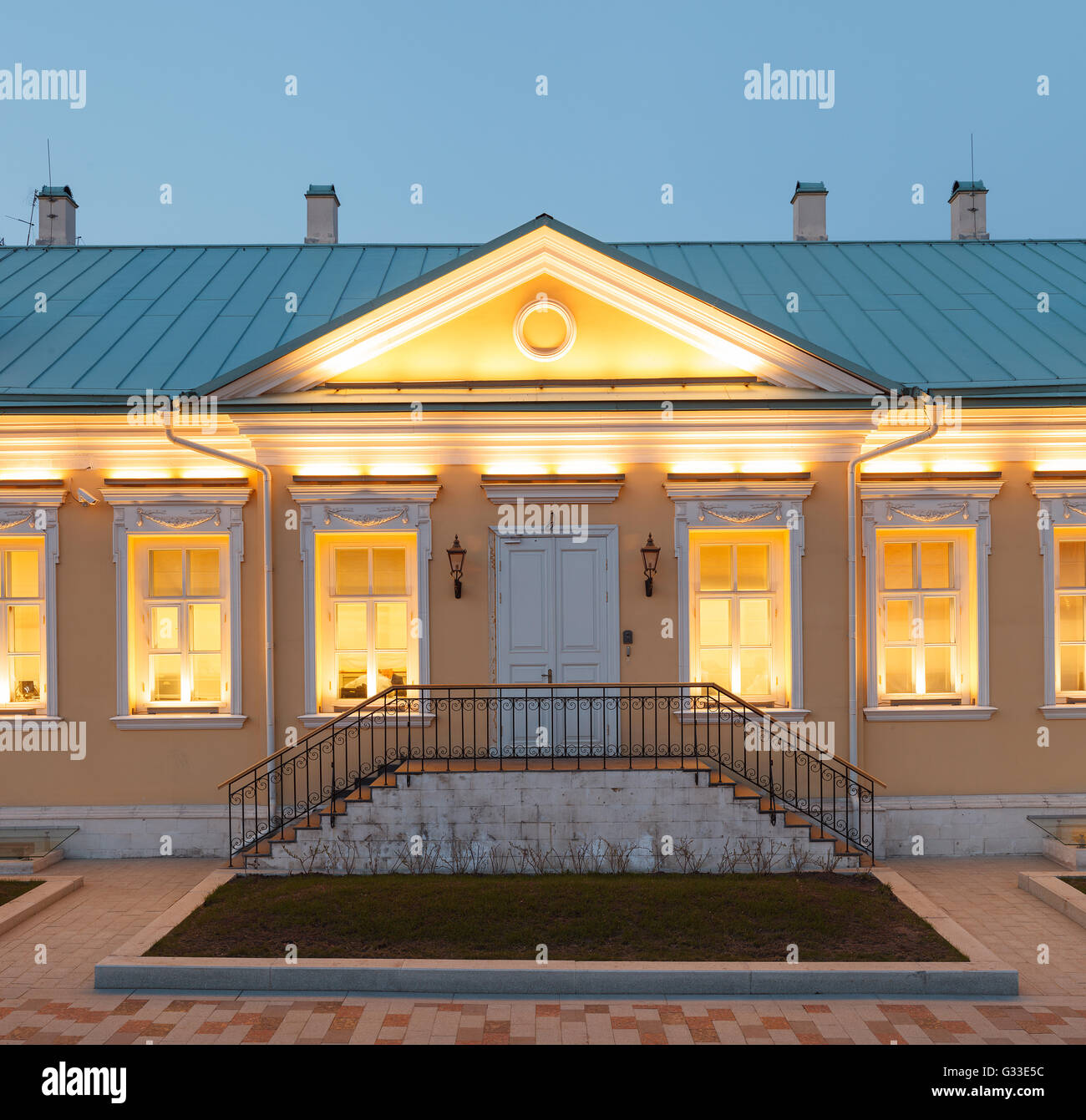 A single storey building in classical palladio style with yellow walls and evening architectural lighting. Moscow, Russia Stock Photo