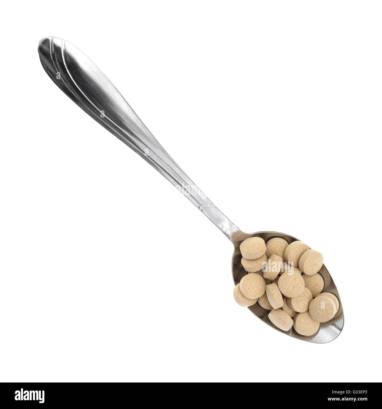 Top view of a metal spoon filled with brewer's yeast nutritional supplement tablets isolated on a white background. Stock Photo