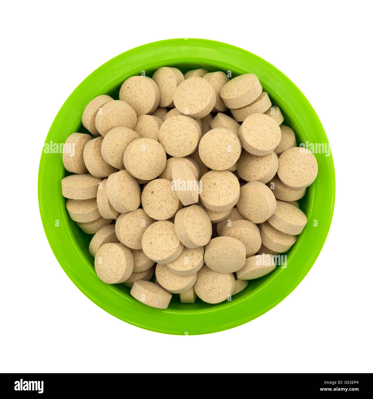 Top view of a green bowl filled with brewer's yeast nutritional supplement tablets isolated on a white background. Stock Photo