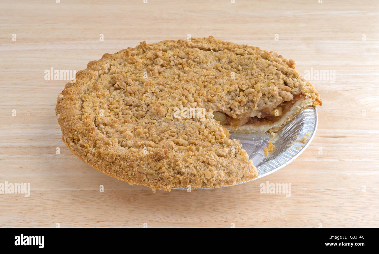 Side view of a Dutch apple pie in a tinfoil baking dish on a wood table