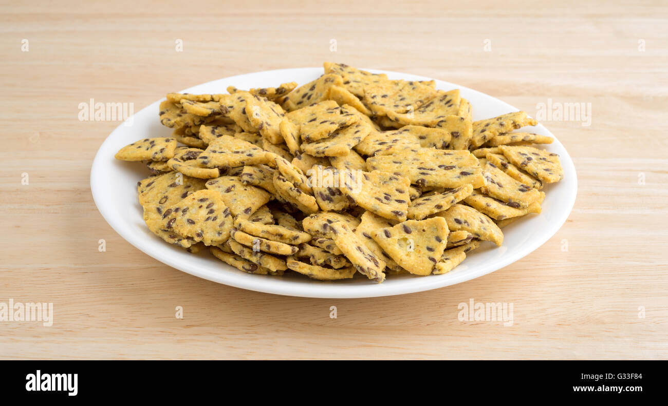 A portion of flax seed corn chips on a white plate atop a wood table