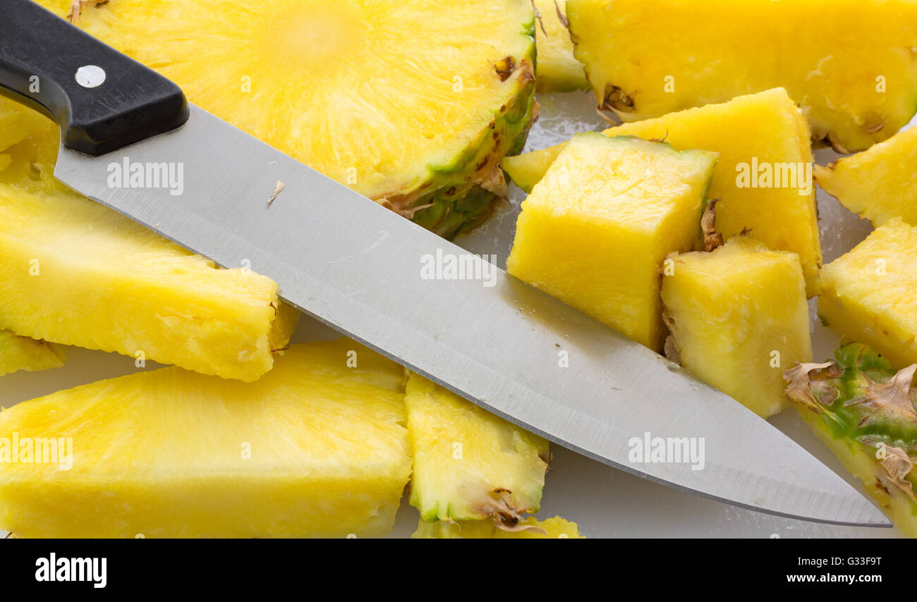 A fresh pineapple on a cutting board that has been sliced with a large