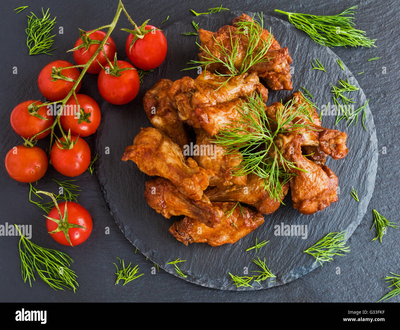 Chicken wings cooked with barbecue sauce on black stone background