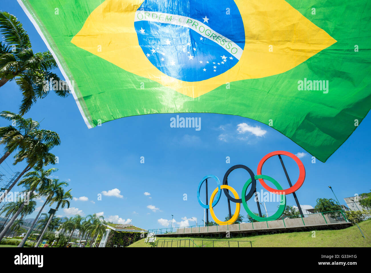 RIO DE JANEIRO - MARCH 18, 2016: A Brazil flag hangs in front of a display of Olympic rings in Parque Madureira Park, Zona Norte Stock Photo