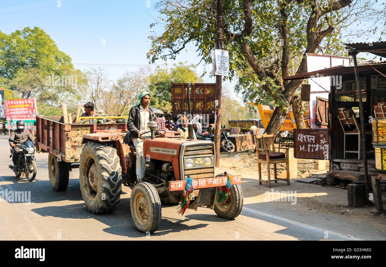 Man driving orange tractor towing trailer with passengers, Agra, Uttar