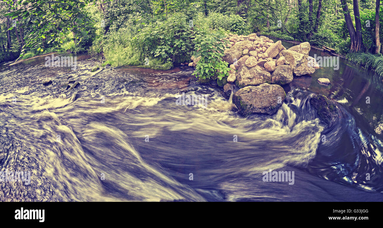 Vintage toned blurred river in forest, nature background. Stock Photo