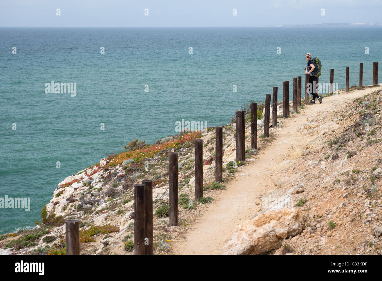 Young woman tourist standing on cliff and looking at beautiful coast along the Seven Hanging Valleys Trail, Algarve Portugal Stock Photo