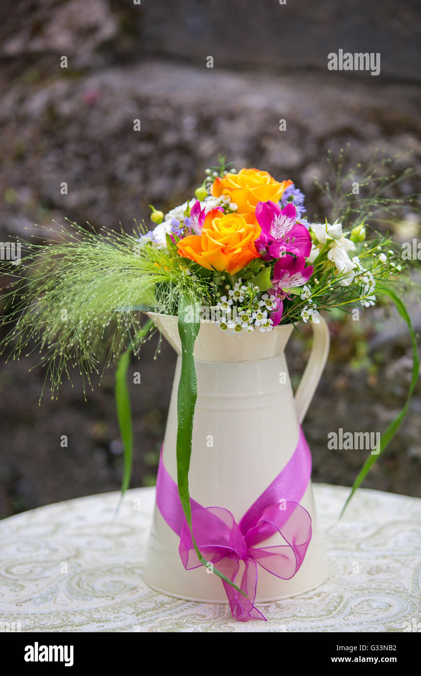 Beautiful yellow rose, pink alstroemeria, wax flower, white spray rose, green foliage flower arrangement in a jug. Wedding decor Stock Photo