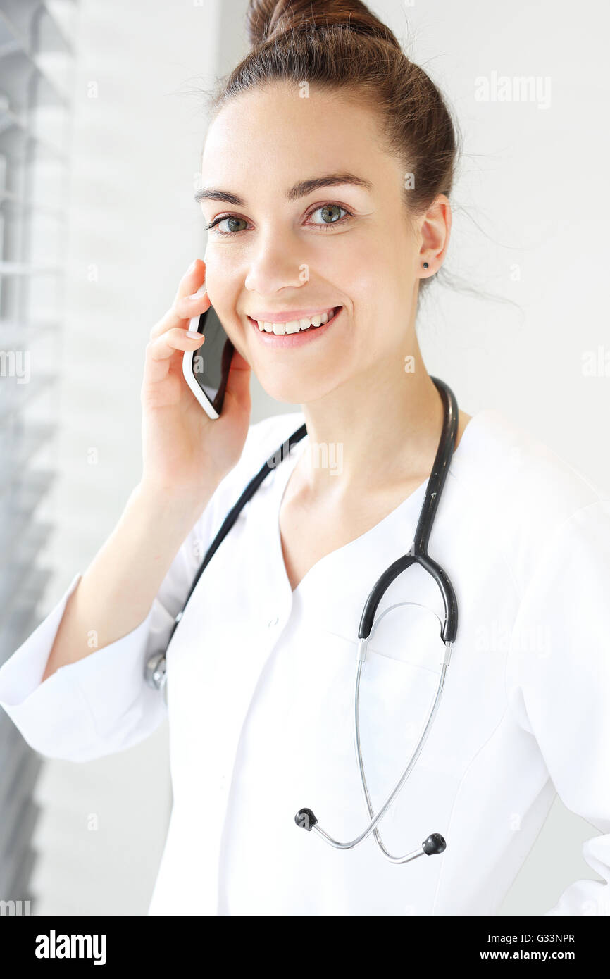 The doctor dressed in a white lab coat talking on the phone while