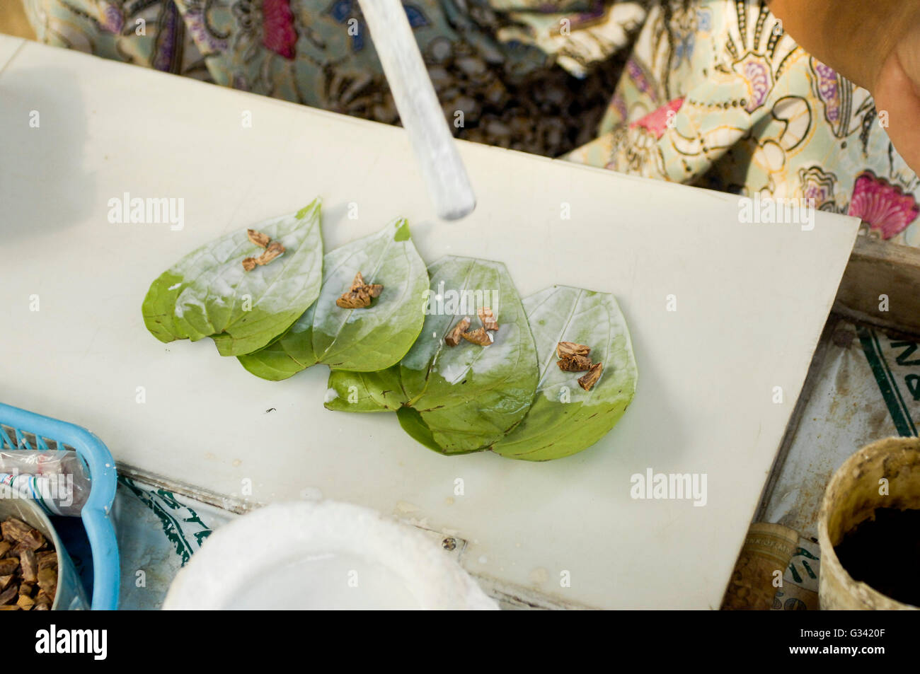 A paan vendor preparing a mixture of tobacco and areca nut on a betel leaf. Stock Photo