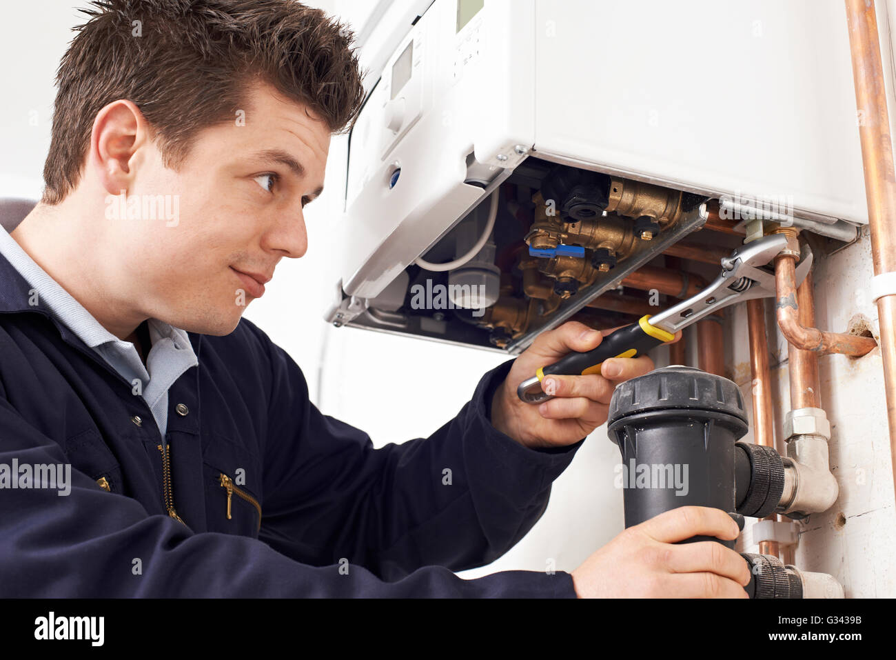 Male Plumber Working On Central Heating Boiler Stock Photo