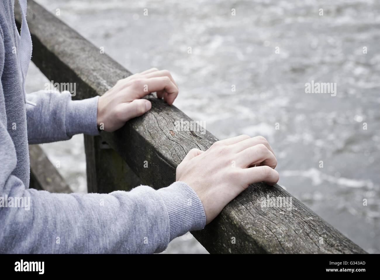 Depressed Young Man Contemplating Suicide On Bridge Over River Stock Photo