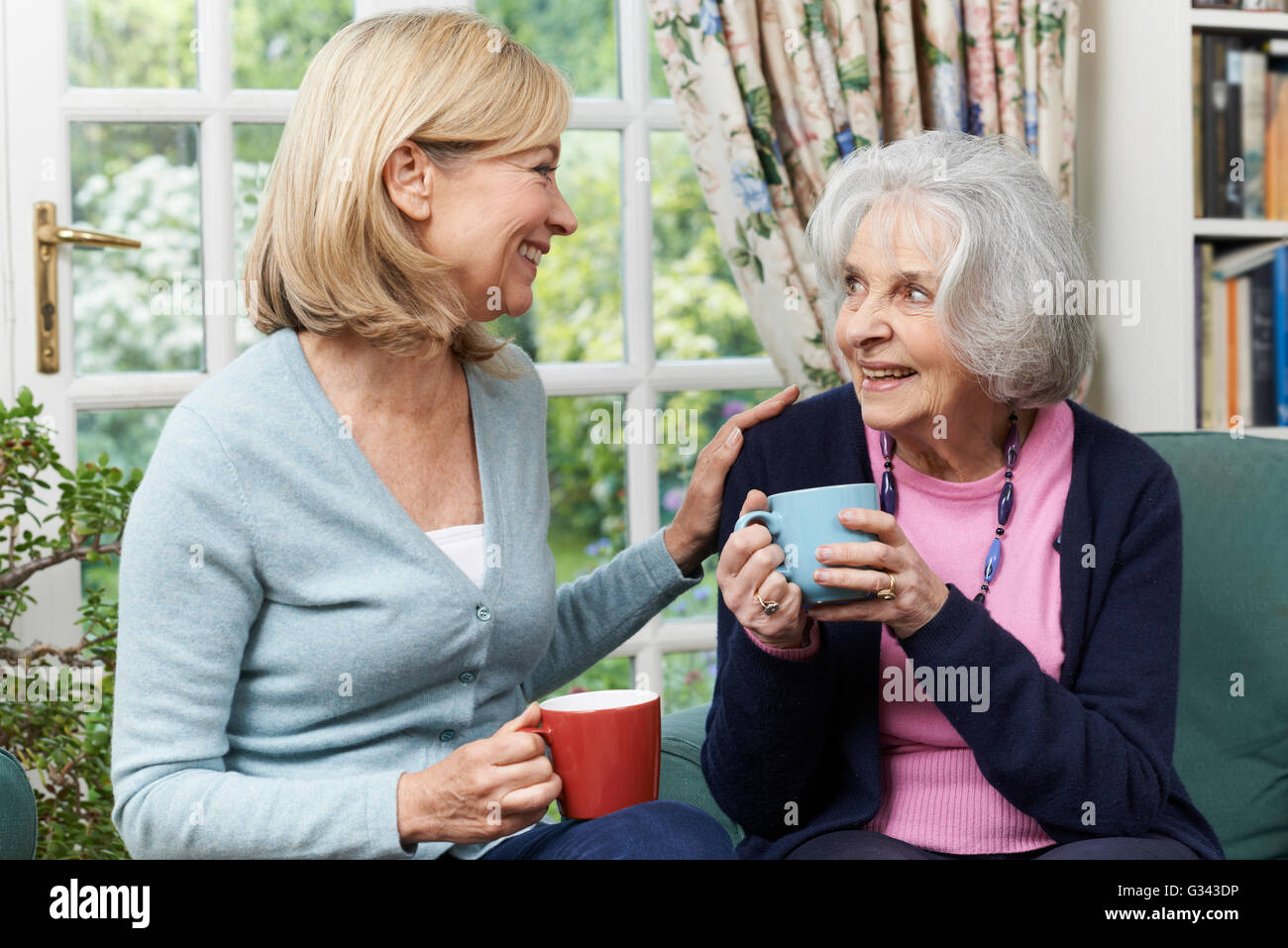 Woman Taking Time To Visit Senior Female Neighbor And Talk Stock Photo