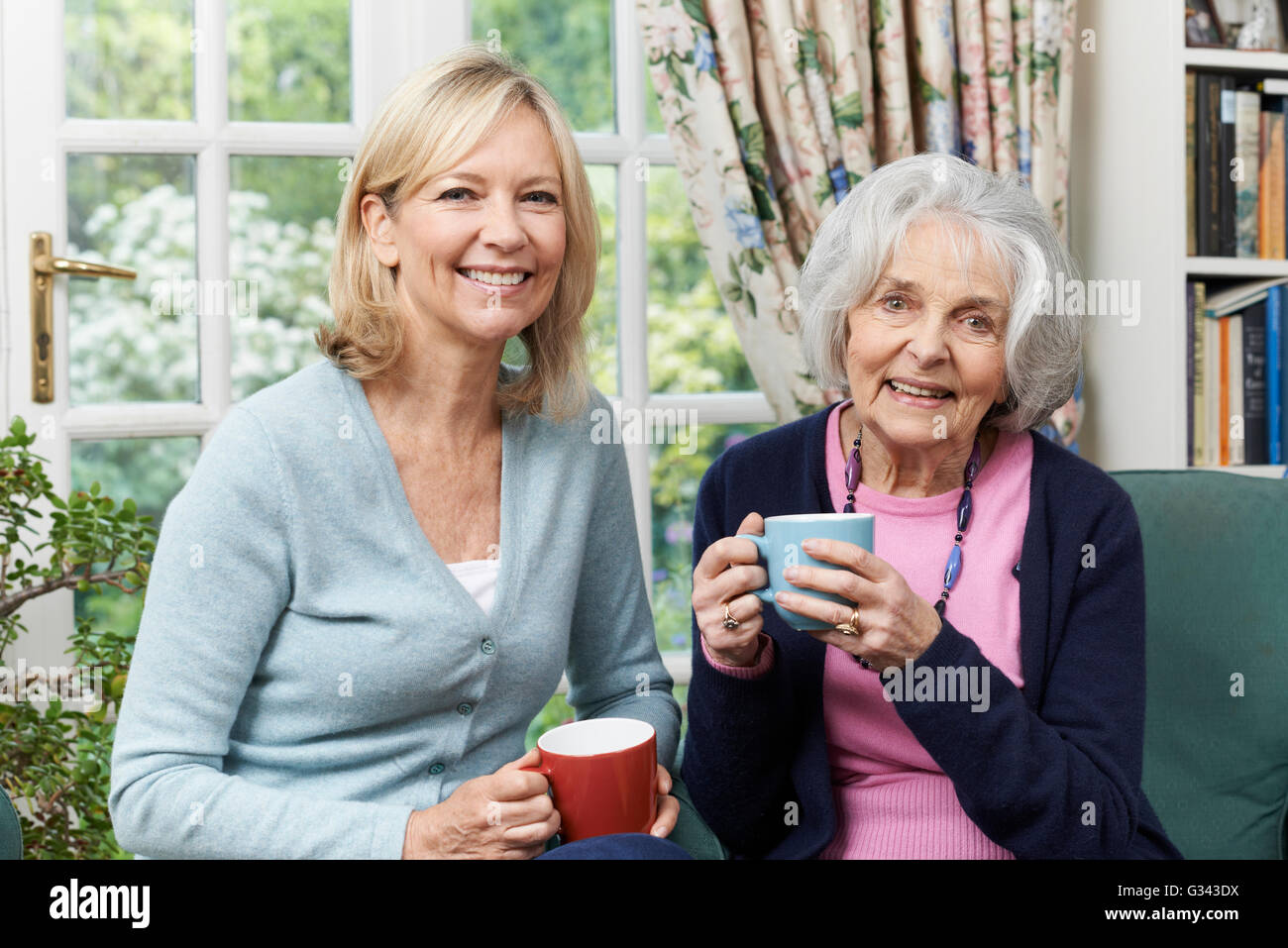 Woman Taking Time To Visit Senior Female Neighbor And Talk Stock Photo