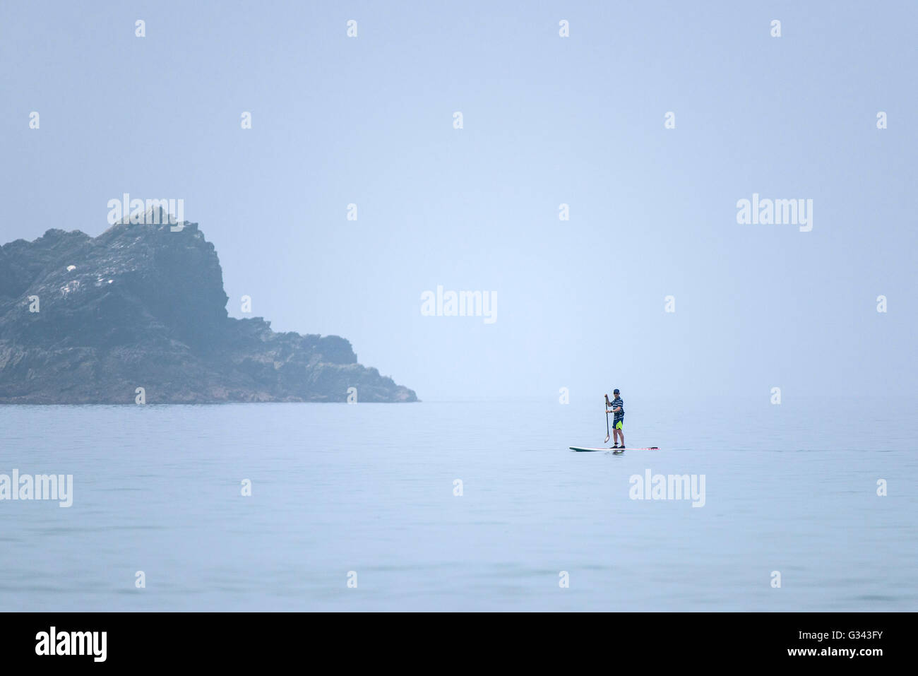 A paddle boarder on a misty, hazy day at Fistral in Newquay, Cornwall, England, UK. Stock Photo