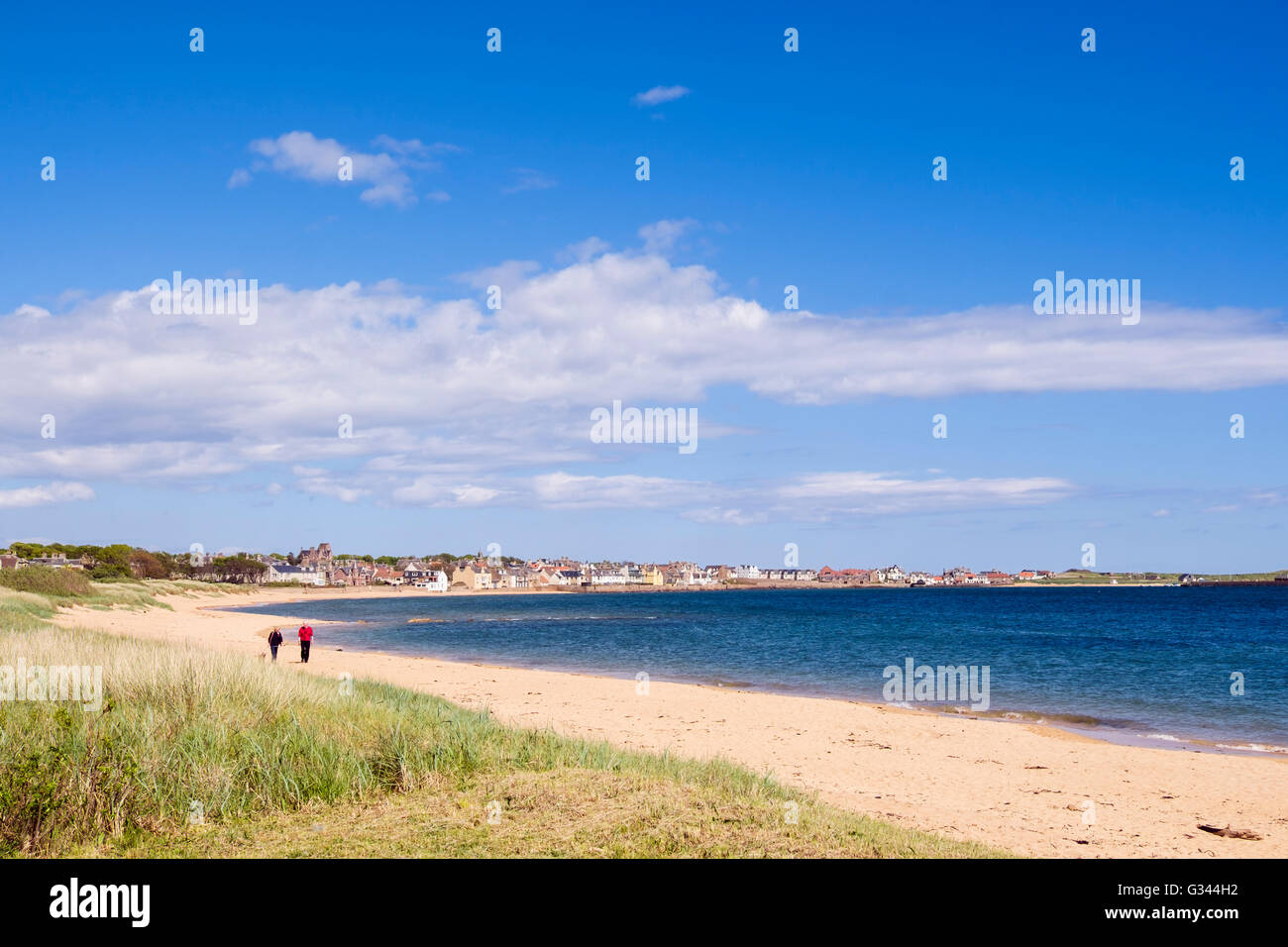 Two people walking on a quiet sandy beach in village on Firth of Forth coast. Elie and Earlsferry, East Neuk of Fife, Fife Scotland, UK Stock Photo