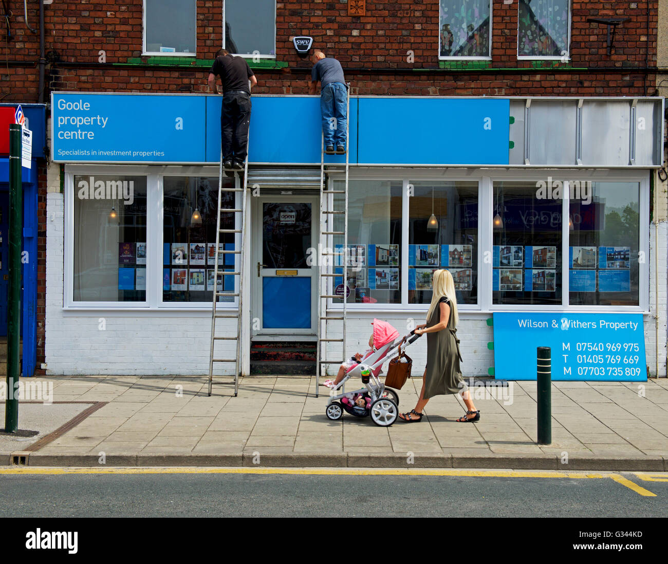 Two men fitting sign on shop in Goole, Lincolnshire, England UK Stock ...