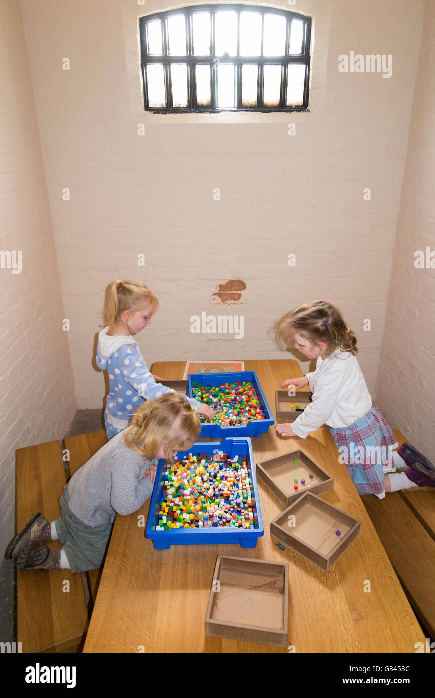 Tourist children / kid / kids / young child play with games in a Victorian gaol / jail prisoner cell in Lincoln Castle prison. Stock Photo