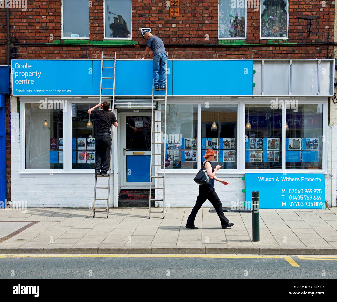 Two men fitting sign on shop in Goole, East Yorkshire, England UK Stock Photo Alamy