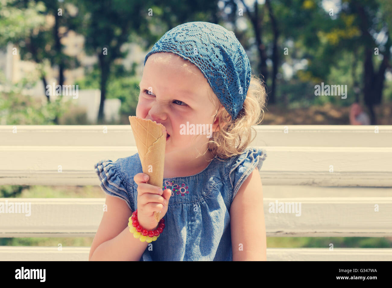 Funny little girl (3 years) eat ice cream. Selective focus. Stock Photo