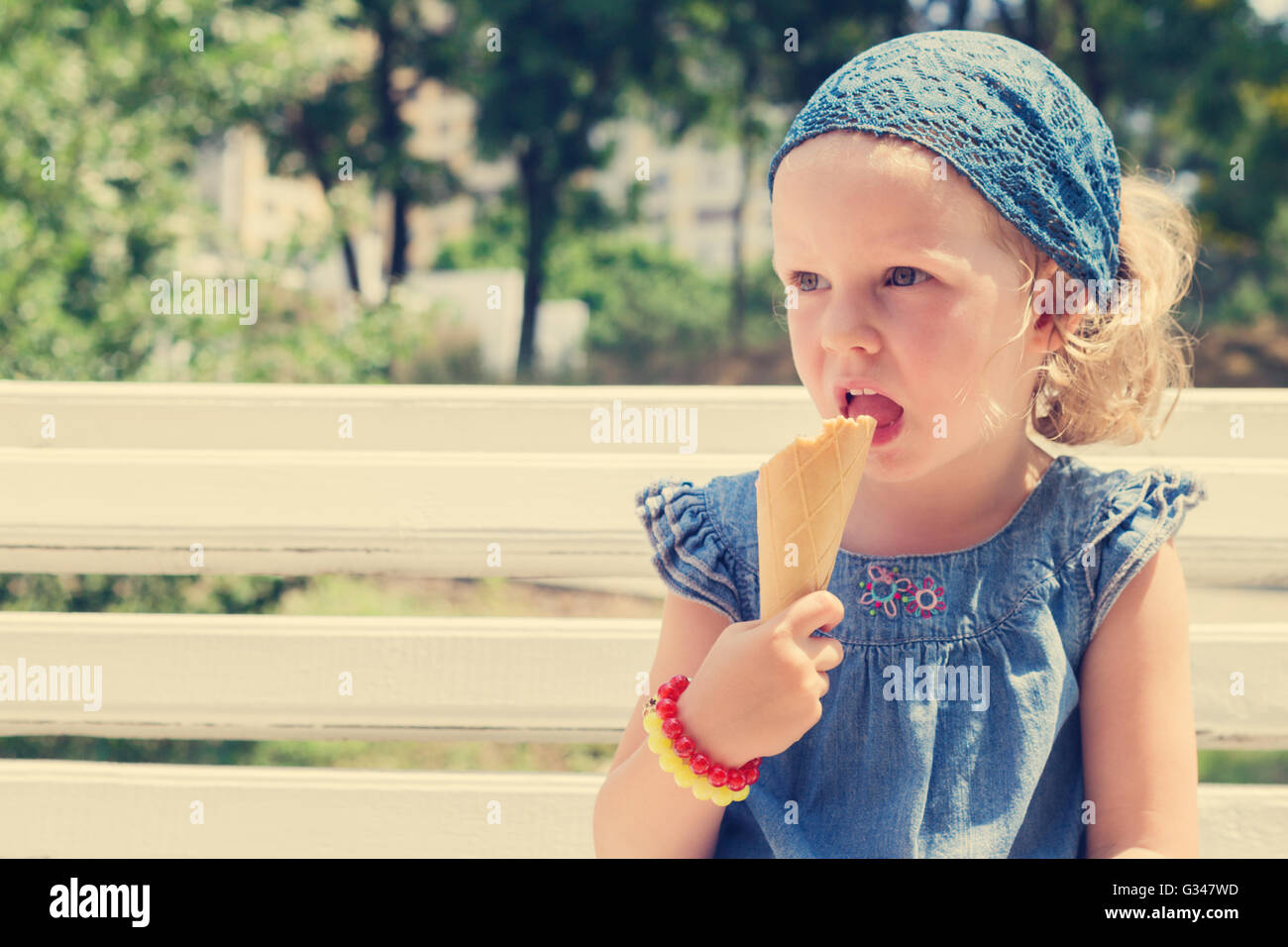 Funny little girl (3 years) eat ice cream. Selective focus. Stock Photo