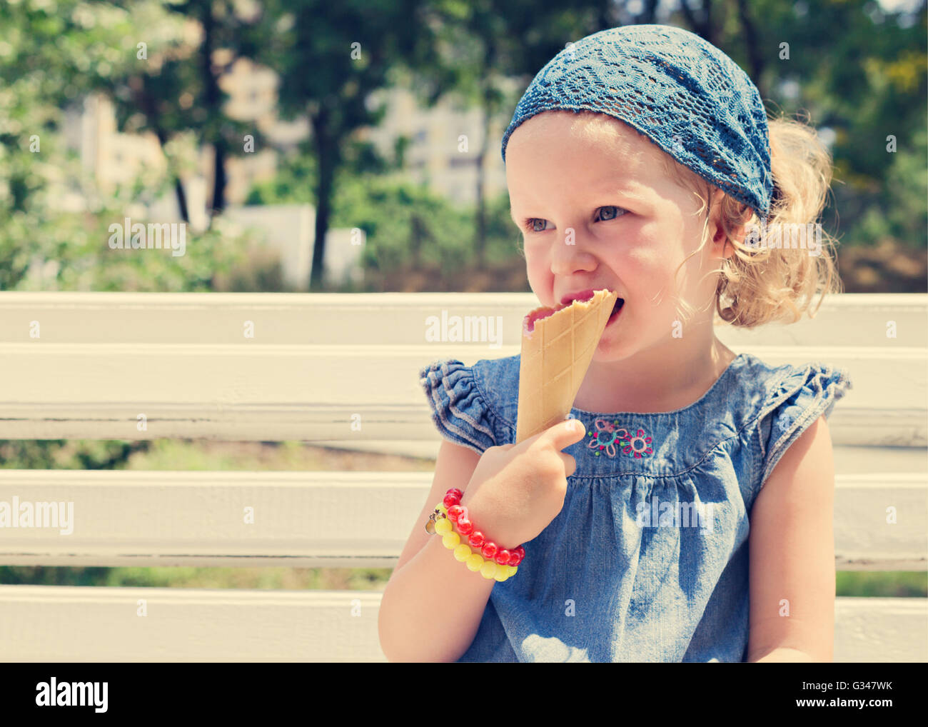 Funny little girl (3 years) eat ice cream. Selective focus. Stock Photo
