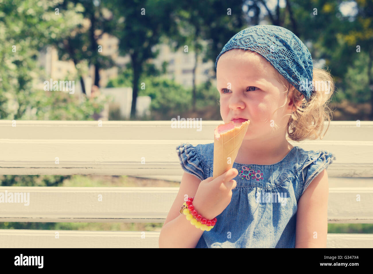 Funny little girl (3 years) eat ice cream. Selective focus. Stock Photo