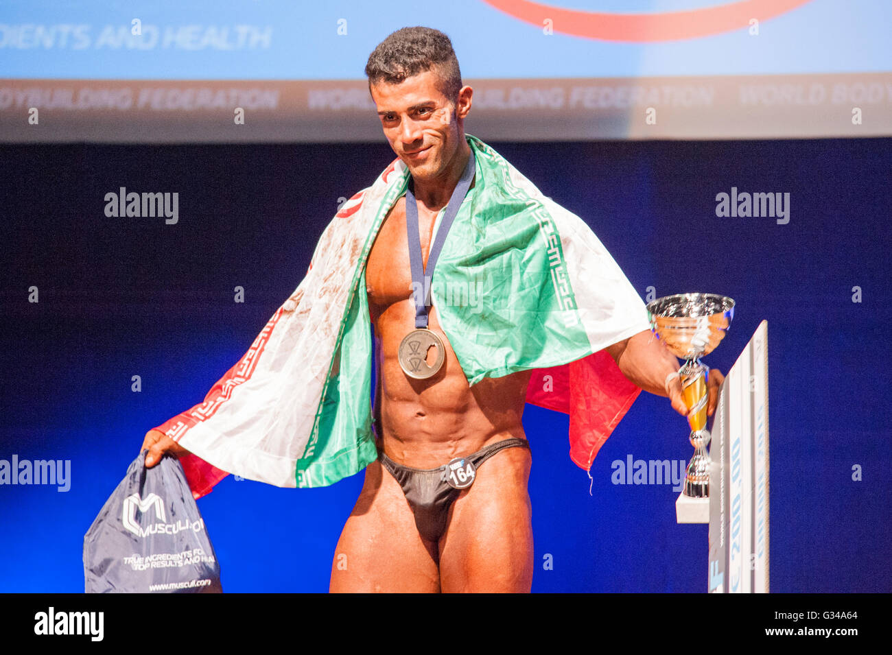 MAASTRICHT, THE NETHERLANDS - OCTOBER 25, 2015: Male bodybuilder celebrates his victory on stage with his national flag of Iran Stock Photo
