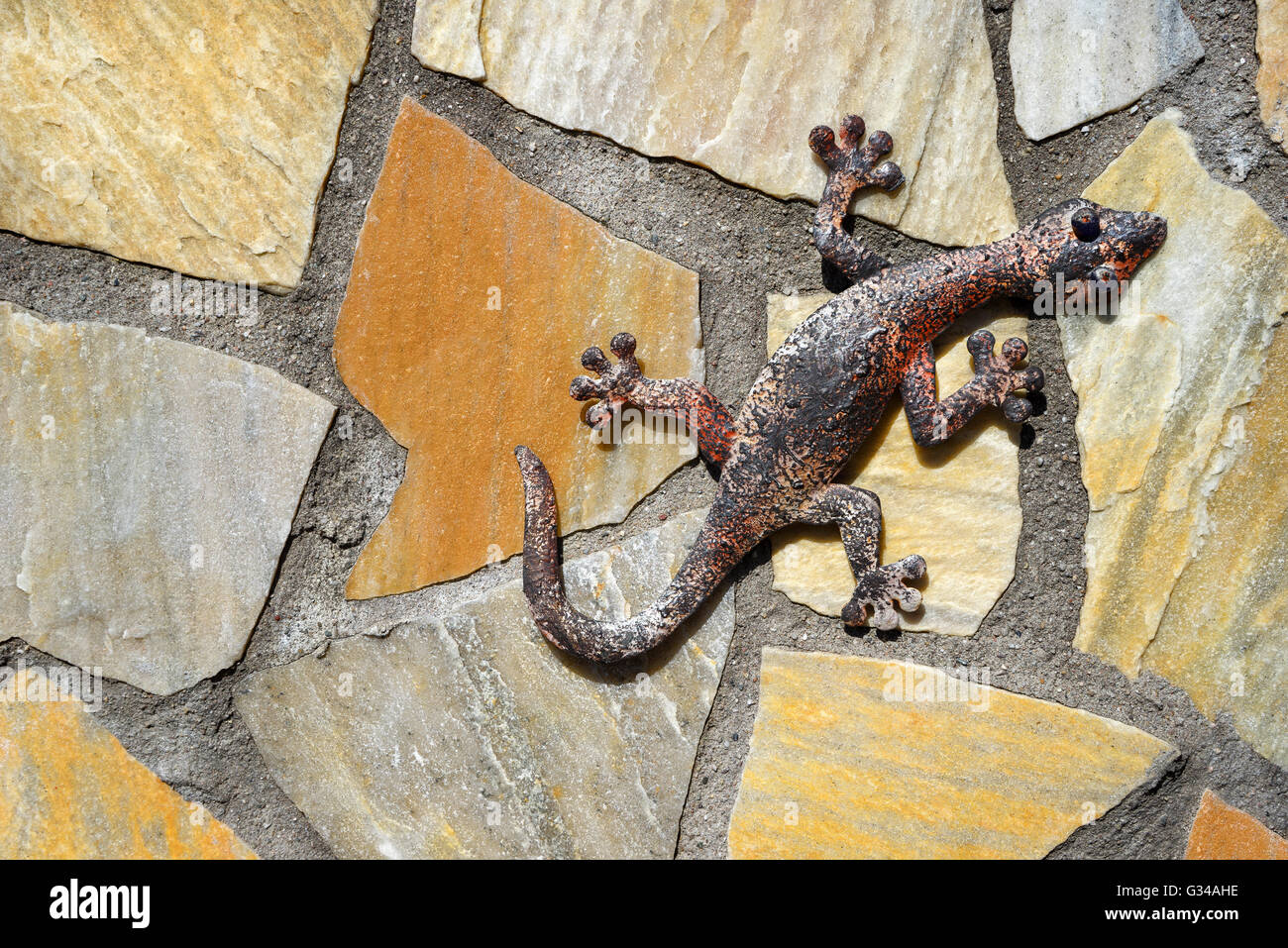 Gecko made of metal on a stone wall Stock Photo