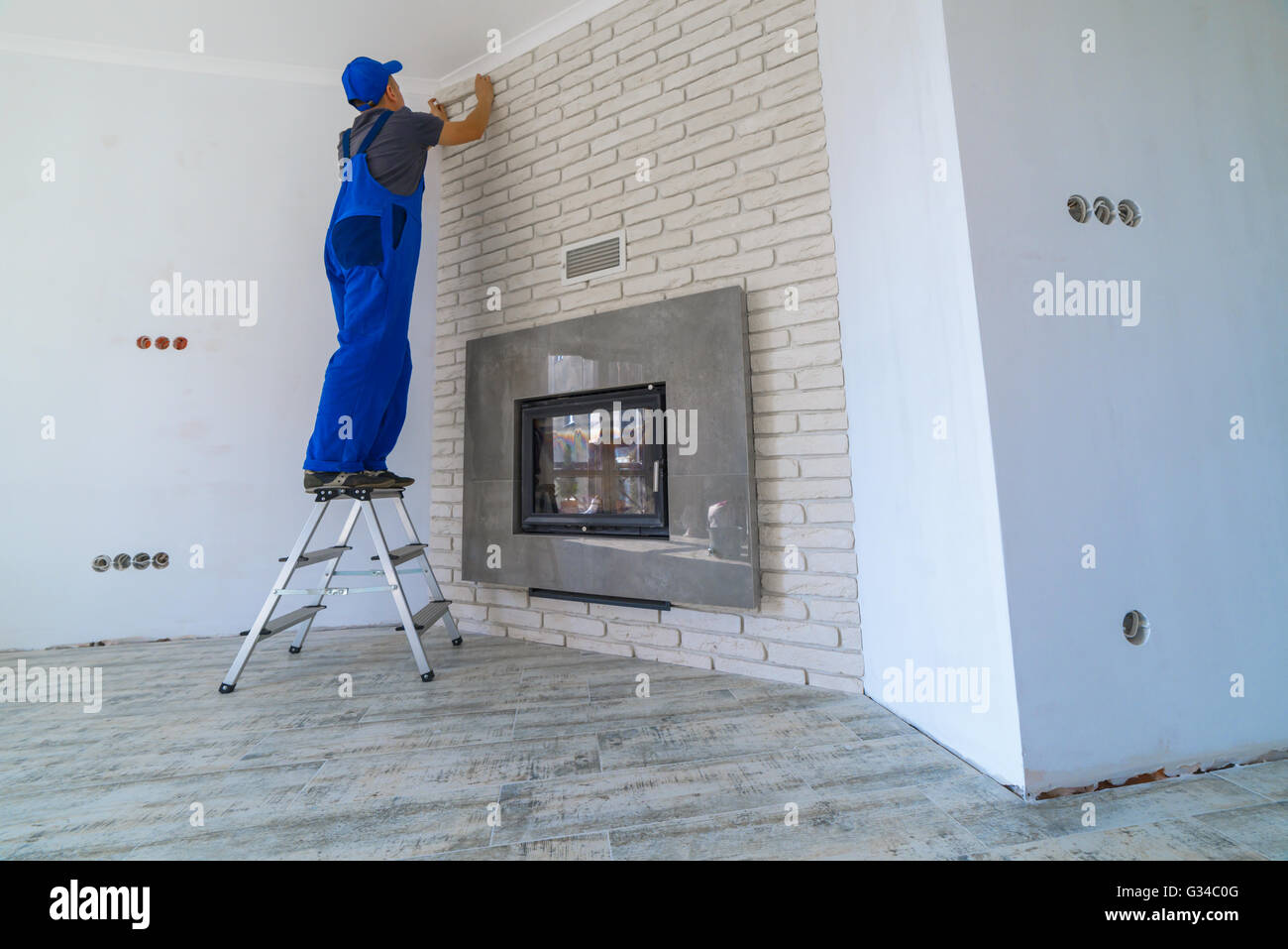 Fireplace installing in white brick wall Stock Photo