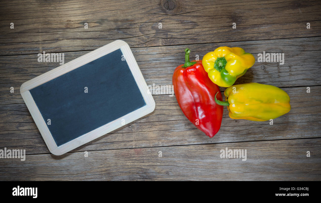 yellow pepper on wooden table and blackboard Stock Photo