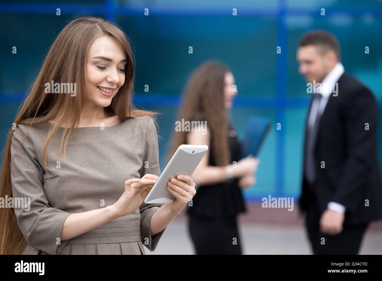 Portrait of confident young woman looking at tablet screen with happy facial expression outdoors. Successful beautiful caucasian Stock Photo