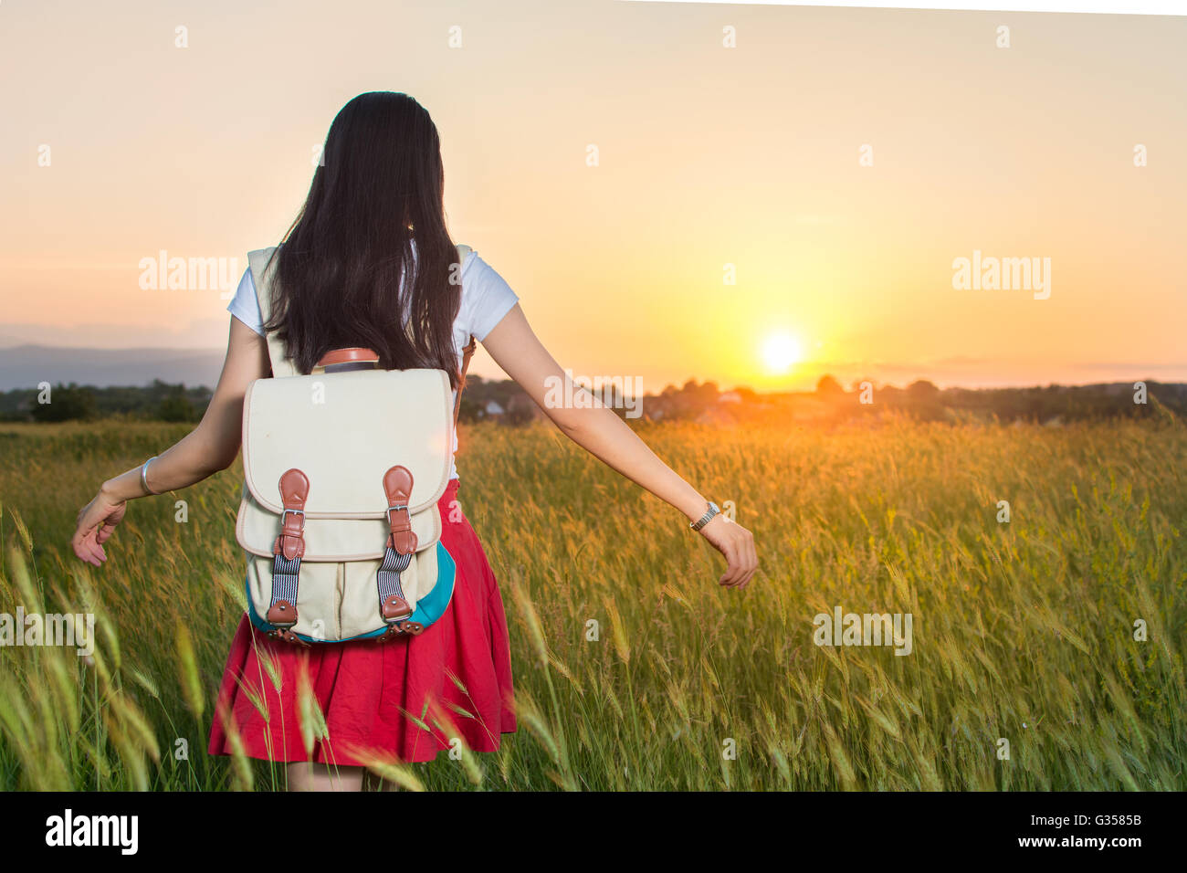 Young woman in a wheat field at sunset Stock Photo