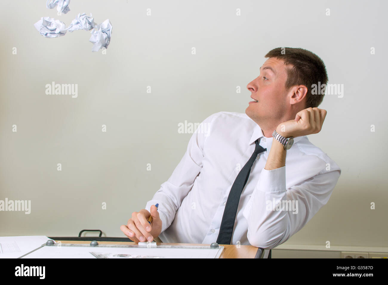 Crumpled papers flying into young businessman face Stock Photo