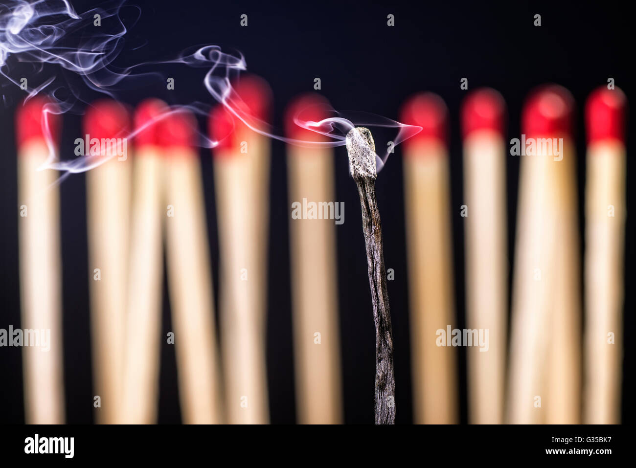 Burned matchstick in front of a new set of matches Stock Photo