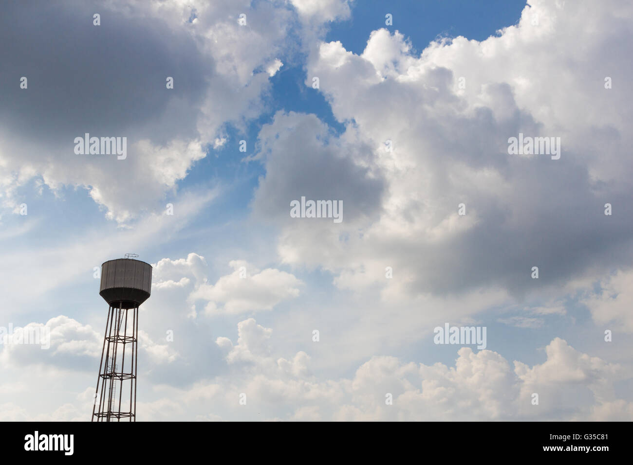 An old rusty water tower over a cloudy blue sky Stock Photo - Alamy