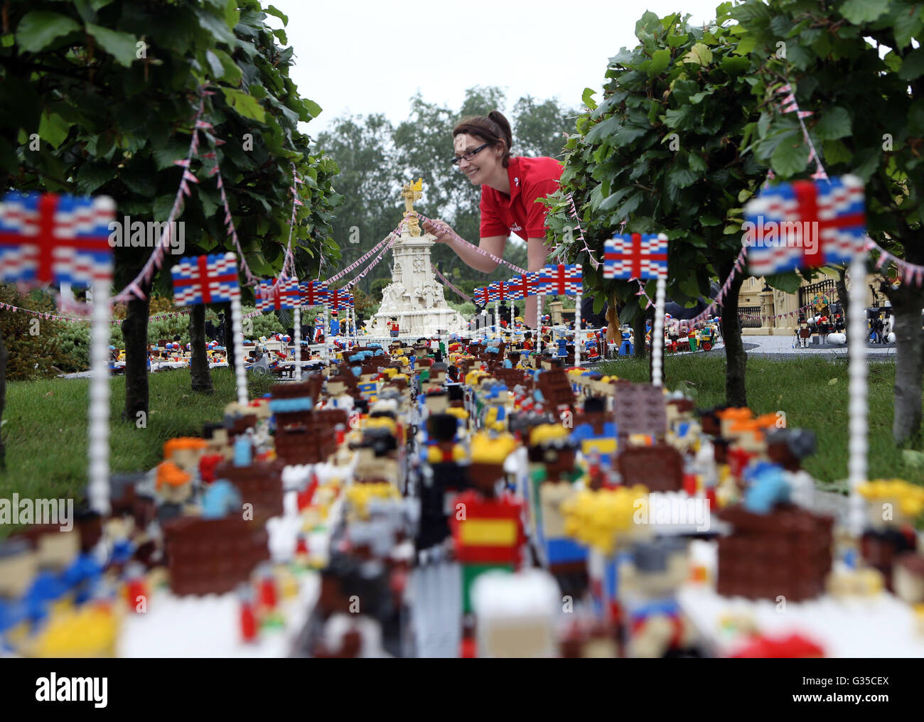 LEGOLAND Windsor Resort model maker Kat James puts the finishing touches to a miniature street party outside a model of Buckingham Palace in Miniland ahead of the Patron's Lunch on The Mall in London to mark the Queen's official 90th birthday on June 12. Stock Photo