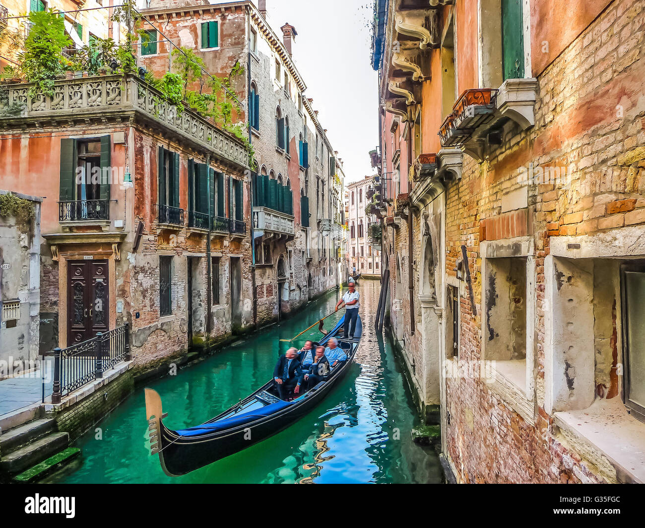 Traditional Gondolas on narrow canal between colorful historic houses in Venice, Italy Stock Photo