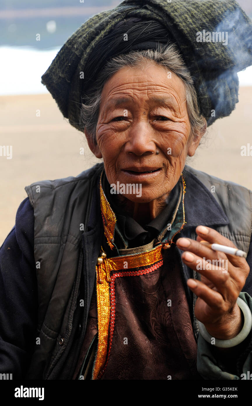 CHINA Yunnan Lugu Lake , Naxi woman, ethnic minority Naxi, cigarette smoking woman Stock Photo