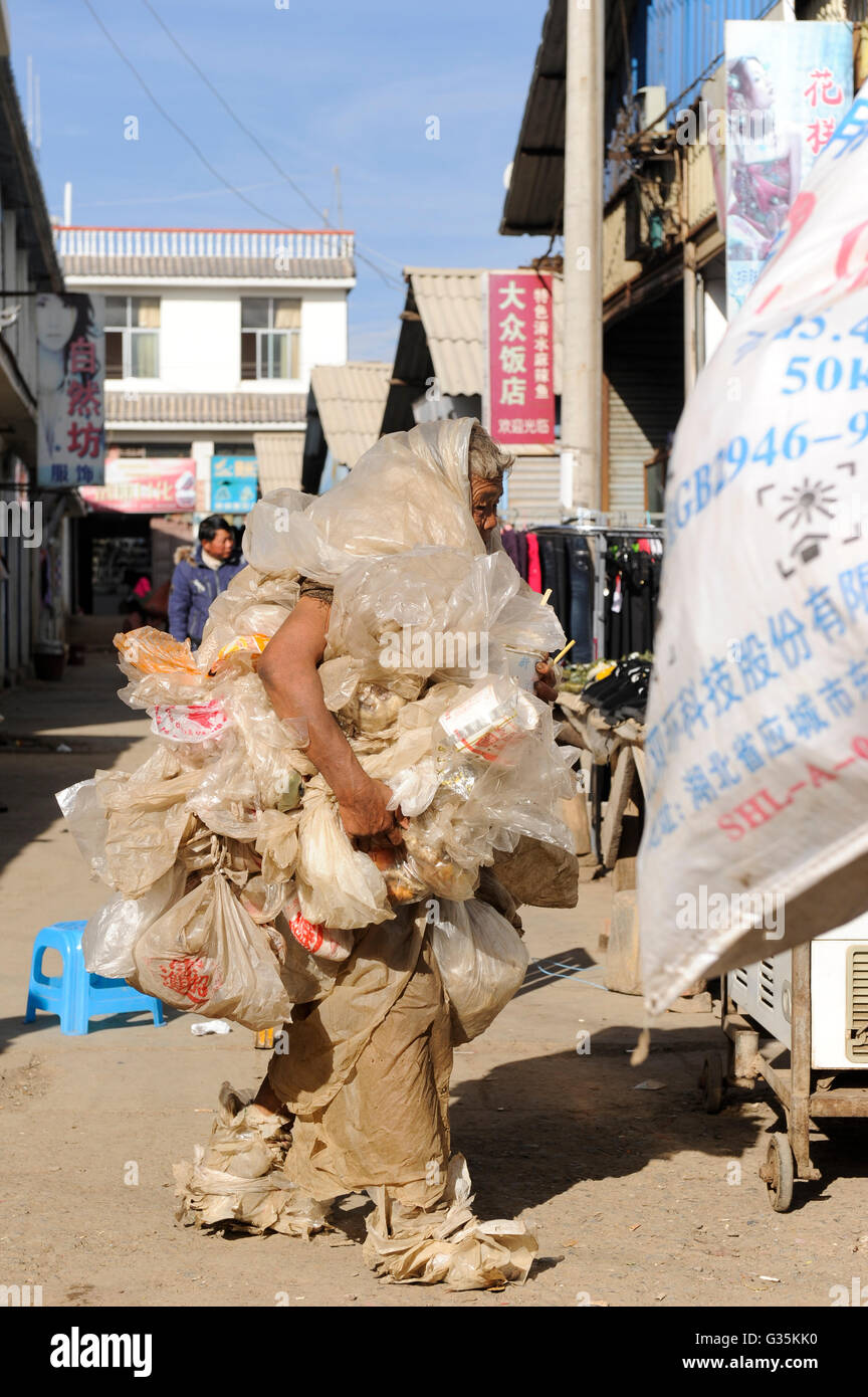 CHINA Yunnan, Yongningxiang, market, mentally disturbed waste picker dressed in plastic foil garbage Stock Photo