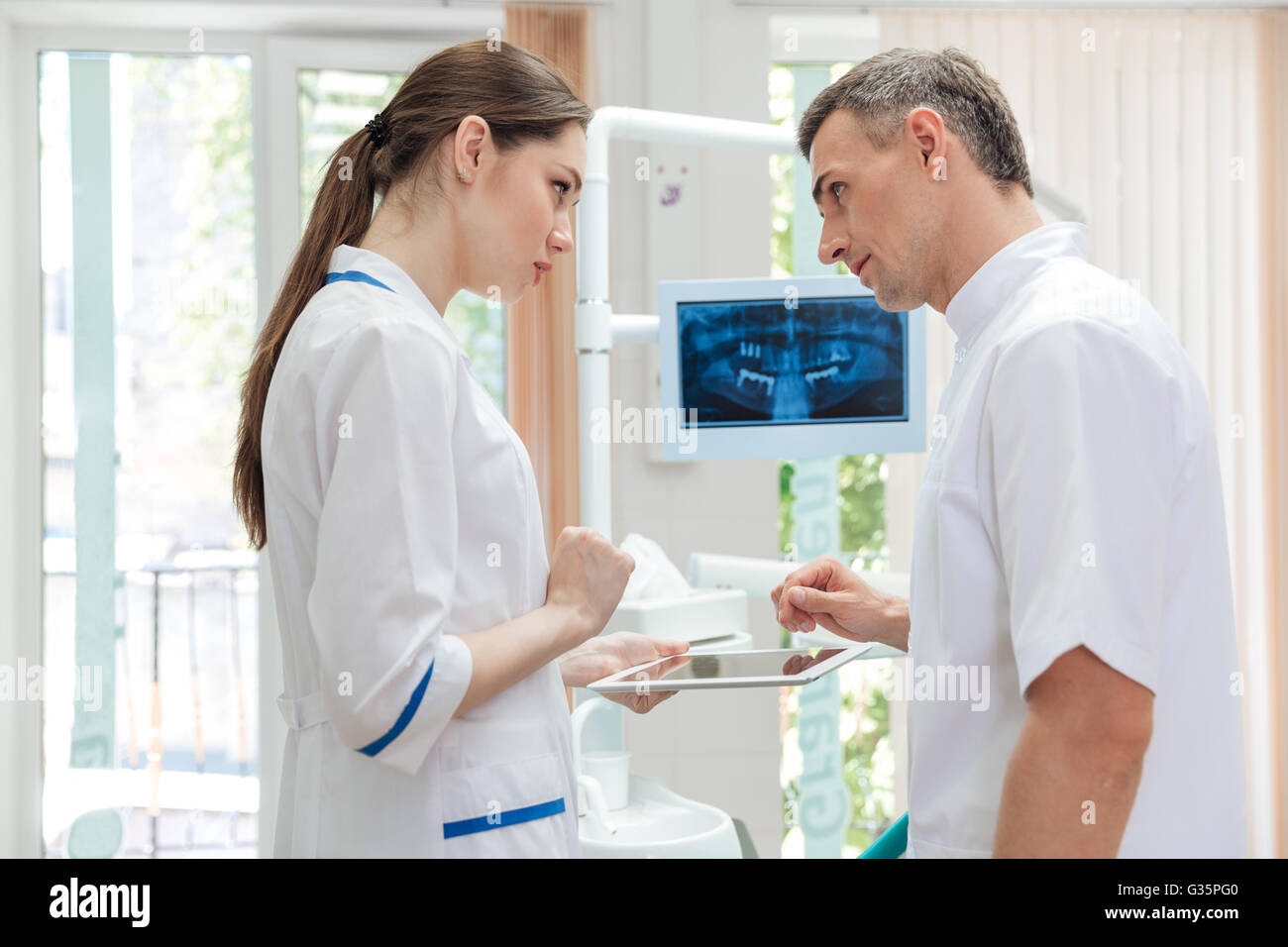 Two doctors dentists looking panoramic photo of teeth on the monitor in clinic Stock Photo